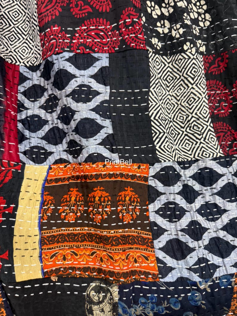 Pode incluir: Um t&ecirc;xtil de patchwork com uma variedade de padr&otilde;es e cores. O design inclui formas geom&eacute;tricas, motivos florais e padr&otilde;es paisley em tons de preto, vermelho, laranja e branco. As pe&ccedil;as s&atilde;o costuradas com linha branca.