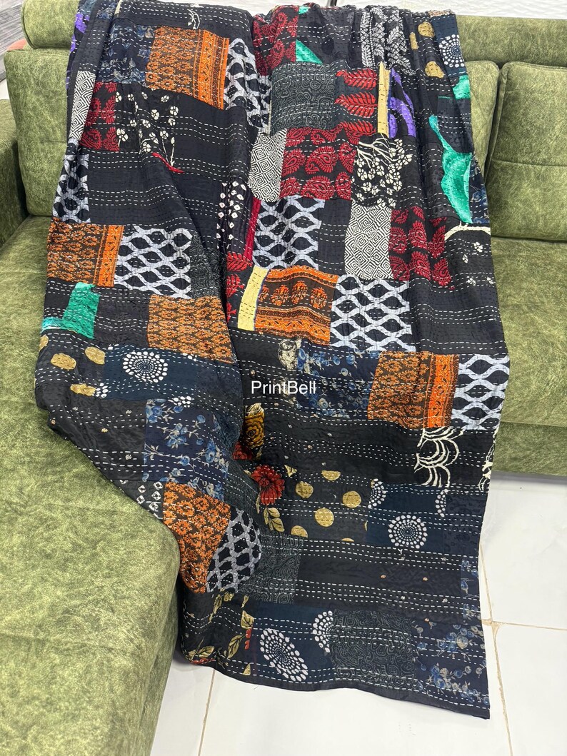 Pode incluir: Uma colcha de retalhos com uma variedade de quadrados de tecido estampado em tons de preto, castanho, vermelho e branco. A colcha est&aacute; sobre um sof&aacute; verde, mostrando seu design intrincado e texturas. A costura da colcha &eacute; vis&iacute;vel.