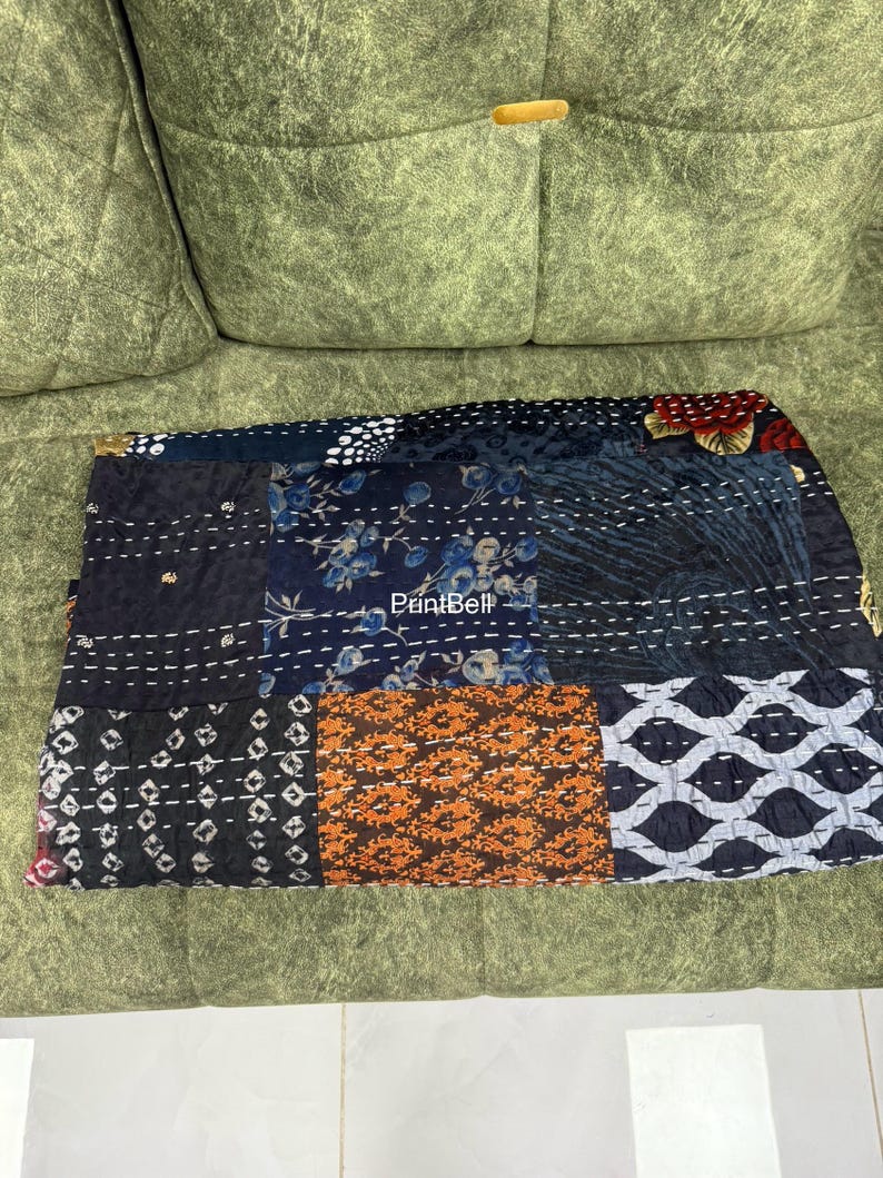 Pode incluir: Um t&ecirc;xtil de patchwork com uma variedade de padr&otilde;es e cores, incluindo desenhos florais, geom&eacute;tricos e abstratos. O t&ecirc;xtil &eacute; feito de diferentes quadrados de tecido costurados com fio branco. A paleta de cores inclui azul marinho, laranja e branco.