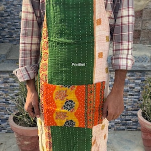Può includere: Un grembiule patchwork con una combinazione di colori verde, arancione e crema. Il grembiule presenta un'ampia tasca ed è realizzato con vari tessuti fantasia. Il testo "PrintBell" è visibile. Il grembiule è indossato da una persona.