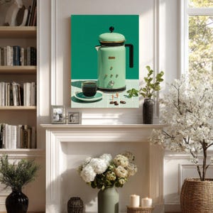 Puede incluir: Una cafetera verde menta con asa y detalles negros, una taza pequeña de café y un platillo se exhiben sobre una superficie de baldosas verdes y blancas. La imagen también incluye granos de café y una ramita de vegetación. La cafetera tiene un diseño retro.