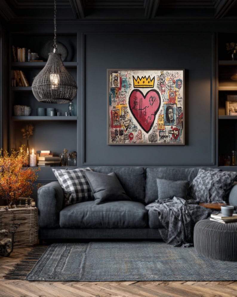 May include: A framed artwork featuring a large pink heart with a gold crown, surrounded by colorful graffiti-style drawings. The artwork hangs above a gray sofa with pillows and a blanket, in a room with a dark blue wall and a woven pendant light.