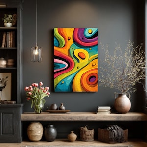 May include: Abstract art canvas with a vibrant, colorful design. The artwork features swirling shapes in shades of yellow, orange, blue, purple, and green. The canvas is rectangular and mounted on a dark gray wall, creating a striking contrast.