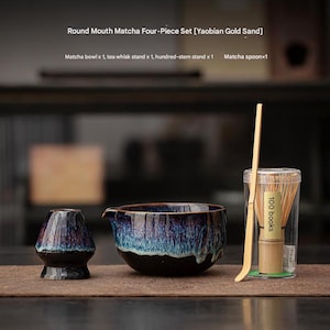 Könnte beinhalten: Ein vierteiliges Matcha-Teeset mit einer Schüssel mit rundem Mund, einem Teebesen, einem hundertstieligen Ständer und einem Matcha-Löffel. Das Set enthält eine dunkelblaue und schwarze Keramikschale und einen Schneebesenständer.