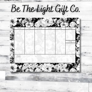 May include: A weekly planner with a floral design in black and white. The planner has sections for each day of the week, with the words "This Week" at the top. The text "She is clothed with Strength and Dignity" is at the bottom.