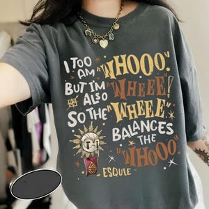 Puede incluir: Camiseta gris oscuro con el texto "I too am a WHOOO, but I'm also WHEEE! So the WHEEE balances the WHOOO." El diseño incluye un gráfico de sol y estrellas. Camiseta unisex de estilo casual.