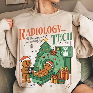 Puede incluir: Sudadera beige con un diseño navideño para un técnico de radiología. El diseño incluye hombres de jengibre, un árbol de Navidad y el texto "Radiology Tech" y "Tis the season to radiate joy."