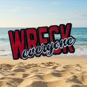 Puede incluir: Parche bordado con las palabras "WRECK everyone" en letras rojas y blancas. El parche está sobre un fondo de playa arenosa y océano, flotando sobre la arena.