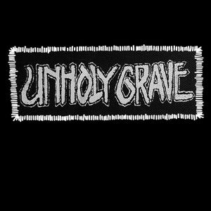May include: A rectangular black patch with the words "UNHOLY GRAVE" in white, stylized, block letters. The patch has a white stitched border. The background is solid black.