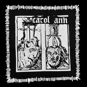 May include: Black and white patch with the text "carol ann" above two detailed illustrations. The illustrations depict figures with scientific equipment. The patch has a white stitched border.