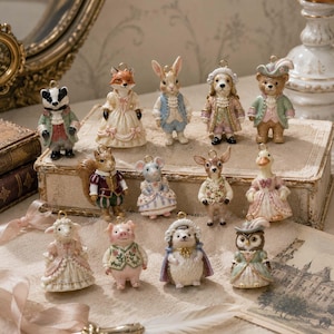 May include: A collection of twelve small, anthropomorphic animal figurines dressed in ornate, historical-style clothing. The figures include a badger, fox, rabbit, dog, bear, squirrel, mouse, deer, duck, sheep, pig, hedgehog, and owl, each with a gold loop.