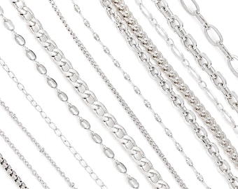 May include: A collection of silver-toned metal chains arranged diagonally. The assortment includes various styles such as a box chain, delicate cable chains, oval link chains, and a thick curb chain, all featuring a polished, reflective finish.