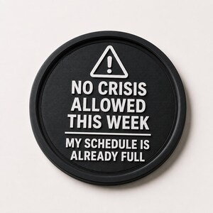 Könnte beinhalten: Ein schwarzer runder Untersetzer mit weißem Text. Der Text lautet "NO CRISIS ALLOWED THIS WEEK" und "MY SCHEDULE IS ALREADY FULL". Oben befindet sich ein weißes Dreieck mit einem Ausrufezeichen.