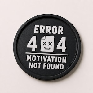 May include: A black, circular patch with white text and graphics. The text reads "ERROR 404 MOTIVATION NOT FOUND." The graphic is a white file icon with a dead face. The patch has a raised, textured surface.
