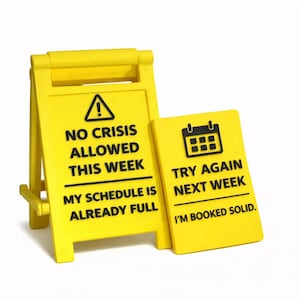 Op de afbeelding: Twee gele borden met zwarte tekst. Op één bord staat "GEEN CRISIS TOEGESTAAN DEZE WEEK MIJN AGENDA IS AL VOL". Op het andere bord staat "PROBEER HET VOLGENDE WEEK OPNIEUW IK BEN VOLGEBOEKT."
