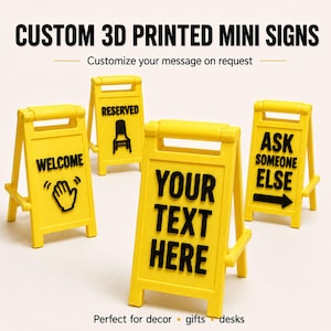 May include: Yellow custom 3D printed mini signs with black text. One sign says "WELCOME" with a hand graphic, another says "RESERVED" with a chair graphic, a third says "YOUR TEXT HERE", and the last says "ASK SOMEONE ELSE" with an arrow.