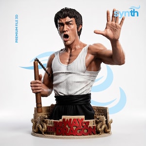 Op de afbeelding: Een gedetailleerde 3D-sculptuur van een man in een witte tanktop en zwarte broek, met nunchucks. De sculptuur staat op een voetstuk met de tekst "THE WAY OF THE DRAGON" en twee gouden drakenbeelden. De sculptuur heeft een dynamische pose.