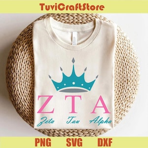 Może przedstawiać: Kremowa koszulka z turkusowym wzorem korony nad różowymi literami "ZTA" i słowami "Zeta Tau Alpha" w kolorze turkusowym. Koszulka jest prezentowana na wiklinowym koszu. Na dole obrazu widnieje tekst "PNG SVG DXF".