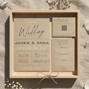 Op de afbeelding: Een trouwuitnodigingsset in een houten dienblad. De uitnodiging toont de woorden "Wedding", "JAMES & ANNA" en de datum 16.08.2026. Inclusief RSVP- en detailkaarten. Een touwstrik voegt een rustieke touch toe.