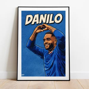 Puede incluir: Un póster enmarcado con el nombre "DANILO" en letras blancas en negrita. La impresión representa a un hombre sonriente con una camiseta azul, formando un corazón con sus manos. El fondo es azul texturizado.