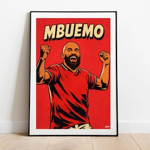 May include: A framed art print featuring a stylized illustration of a bald man with a beard, wearing a red shirt, celebrating with raised fists. The word "MBEUEMO" is printed in large, yellow letters above the figure against a red background.