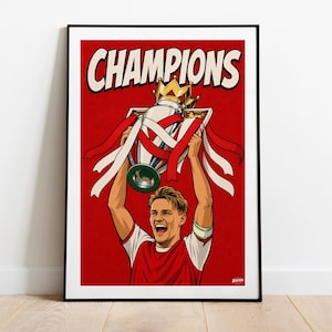 May include: A framed art print featuring a cartoon illustration of a person holding a trophy aloft. The word "CHAMPIONS" is at the top. The background is red. The person is wearing a red and white jersey.