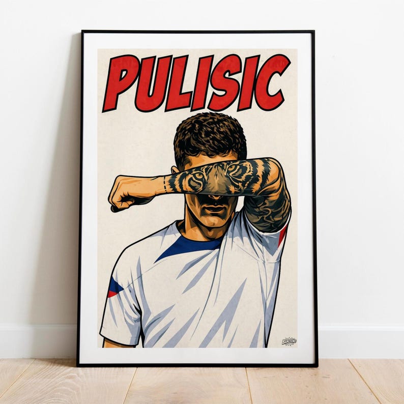 May include: A framed poster featuring a stylized illustration of a soccer player with a tiger tattoo on the forearm, which is held across the face. The name PULISIC is printed in large red letters at the top. The player wears a white jersey.