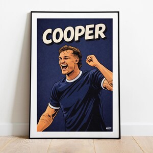 May include: A framed art print featuring a stylized illustration of a man celebrating. The artwork is set against a dark blue background, with the name "COOPER" in bold white letters above the figure. The man is wearing a blue shirt.