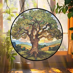 May include: A round stained glass window depicting a large tree with a detailed trunk and leafy canopy. The artwork features a landscape with rolling hills and a colorful sky. The window is framed in black and hangs from a chain.