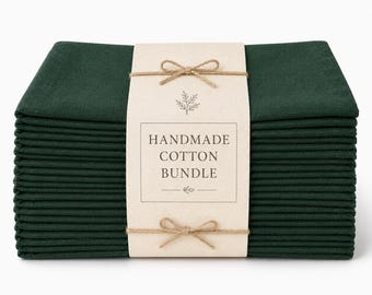 Peut inclure: Une pile de serviettes en coton vert forêt foncé maintenues par une bande de papier beige clair. La bande porte le texte HANDMADE COTTON BUNDLE, une petite illustration botanique, et est nouée avec de la ficelle fine en deux nœuds.