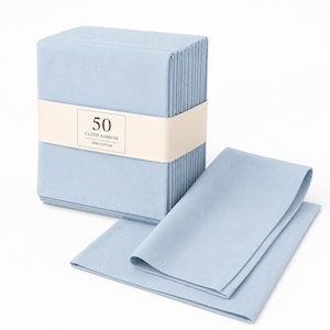 Puede incluir: Un paquete de cincuenta servilletas de tela azul claro sujetas con una banda de papel color crema. La banda muestra el texto 50 CLOTH NAPKINS 100% COTTON. Una servilleta doblada descansa frente al paquete, mostrando la misma tela azul claro.
