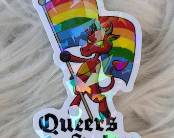 Puede incluir: Una pegatina holográfica con un diablo rojo sosteniendo una bandera arcoíris. La pegatina tiene el texto "Queers for Satan" en una fuente estilizada, con el nombre de usuario de Instagram del artista en la parte inferior.
