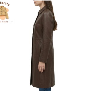 May include: A dark brown leather coat with a button-down front and a collared neckline. The coat is knee-length and has a tailored fit. The California Leather Jackets logo is in the upper left corner.