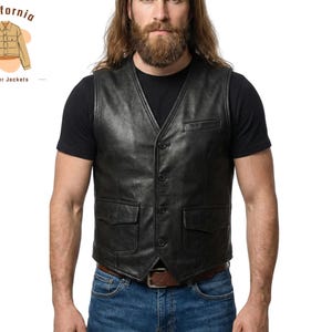 Può includere: Un gilet in pelle nera con scollo a V, chiusura con bottoni e due tasche frontali. Il gilet è indossato sopra una maglietta nera, abbinato a jeans blu e una cintura marrone. L'immagine include un logo per "California leather jackets."