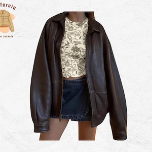 Puede incluir: Chaqueta de cuero marrón oscuro con cremallera y cuello. La chaqueta es de gran tamaño y tiene un ajuste relajado. La modelo lleva un top con estampado floral y una falda vaquera. Se incluye el texto "California leather jackets".