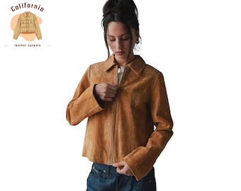 Könnte beinhalten: Hellbraune Wildlederjacke mit Kragen und Reißverschluss. Die Jacke hat lange Ärmel und wird über einem weißen Oberteil getragen. Das Bild enthält den Text "California leather jackets" in der oberen linken Ecke.