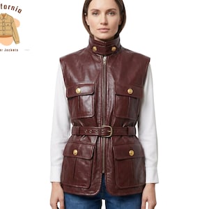 May include: A burgundy leather vest with a high collar, four front pockets, and a belted waist. The vest has gold-colored button details and a zipper closure. The image also includes the text "California leather jackets".