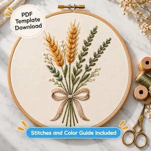 May include: An embroidery hoop containing a fabric panel with a stitched bouquet of golden wheat stalks and green leafy sprigs tied with a beige bow. The text PDF Template Download and Stitches and Colour Guide Included are visible.