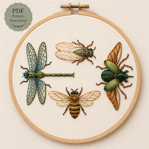 May include: A circular wooden embroidery hoop containing a white fabric panel with hand-stitched insect designs. The embroidery features a blue and green dragonfly, a tan cicada, a brown and yellow honeybee, and a metallic green and brown beetle.