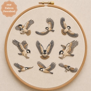May include: An embroidery hoop containing light-coloured fabric with nine embroidered birds in various flight positions. The birds feature black, white, and tan thread details. A badge in the top left corner reads PDF Pattern Download.