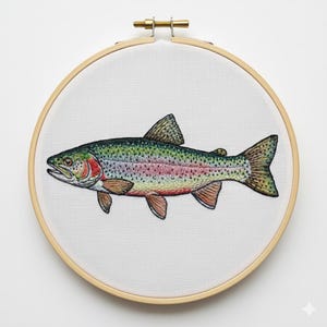 May include: Embroidered rainbow trout on white fabric stretched within a wooden embroidery hoop. The fish features detailed stitching in shades of green, red, pink, and brown. The hoop has a brass clasp at the top.