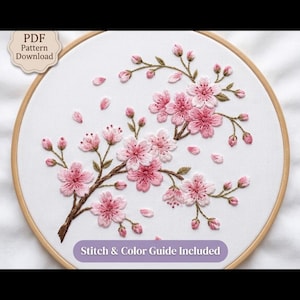 Op de afbeelding: Een borduurring met witte stof en een handgeborduurd kersenbloesemtakontwerp in roze en bruine tinten. De tekst "PDF Pattern Download" en "Stitch & Color Guide Included" is zichtbaar op de afbeelding.