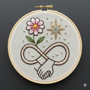 May include: Embroidered artwork in a wooden hoop. The design features a pink and white flower, a gold and silver star, and an infinity symbol with two hands clasped together. Small gold beads and star accents are scattered around the design.