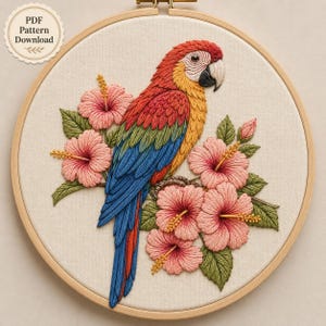May include: A circular embroidery hoop containing a fabric panel with a hand-stitched macaw parrot featuring red, yellow, and blue feathers, surrounded by pink hibiscus flowers and green leaves. A circular badge in the corner reads PDF Pattern Download.