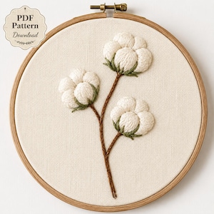 May include: A circular wooden embroidery hoop containing a piece of off-white fabric with a hand-stitched design of three cotton bolls on brown stems with green calyxes. A label in the top left corner reads PDF Pattern Download.