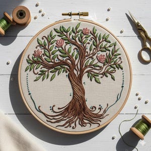 May include: Embroidered tree art in a wooden hoop. The tree features a brown trunk and roots, green leaves, and pink flowers. The embroidery is on a cream-colored fabric. Gold scissors and thread spools are in the background.