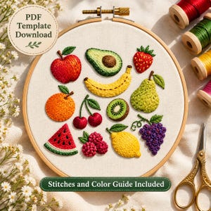 Puede incluir: Un bastidor de bordado con un panel de tela blanca que presenta diseños de frutas bordadas, incluyendo una manzana, aguacate, plátano, fresa, naranja, cerezas, kiwi, pera, rodaja de sandía, frambuesas, limón y uvas. Incluye texto PDF Template Download.