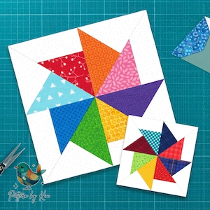 May include: Two colorful quilt blocks with a pinwheel design. The larger block features vibrant triangles in red, orange, pink, purple, blue, green, and yellow. A smaller block with a similar design is also present. The background is a teal cutting mat.