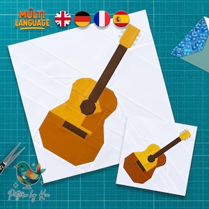 May include: A paper piecing quilt pattern featuring two acoustic guitar designs in shades of yellow and brown on a white background. The text "MULTI LANGUAGE" and "Pattern by Kia" are visible, along with small flag icons and a bird illustration.