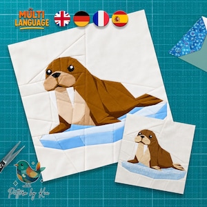 Op de afbeelding: Een foundation paper piecing quiltblokpatroon met een bruine walrus met witte slagtanden die op een lichtblauwe ijsschots rust tegen een witte achtergrond. Het ontwerp bevat twee versies van de walrus, een grotere en een kleinere, met geometrische stofsegmenten en strakke, rechte naden door de hele compositie.
